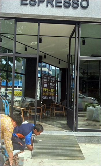 ▲장애인인권권익센터에서 한 커피전문점 출입구에 경사로를 설치하고 있다.