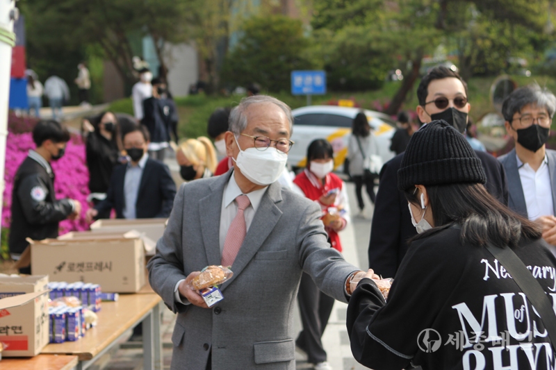 한국영상대학교 유재원 총장이 등교케어 행사에서 등교학생들에게 빵과 음료를 나눠주고 있다.