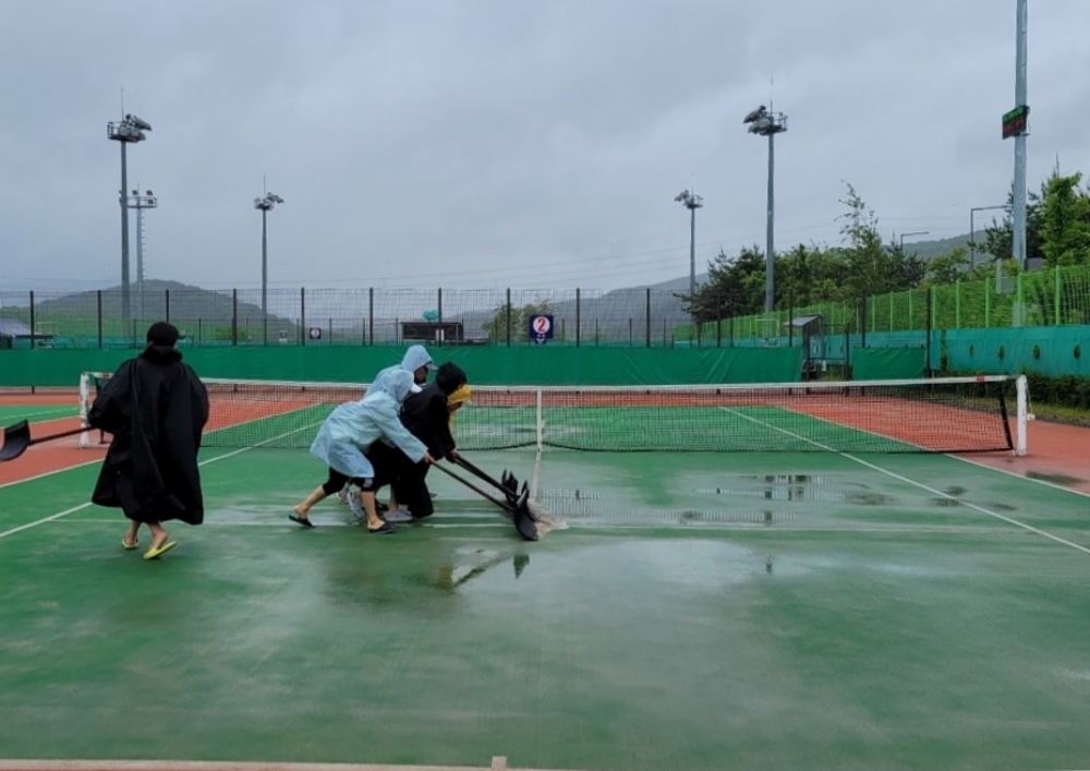 ▲테니스 관계자들이 많은 비로 인해 테니스 구장 바닥에 고인 물을 치우느라 분주하다. 