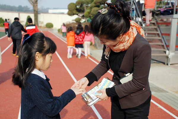  연봉초등학교 사제동행 행복걷기에 참가한 학생에게 참가 확인스티커를 붙여주고 있다.