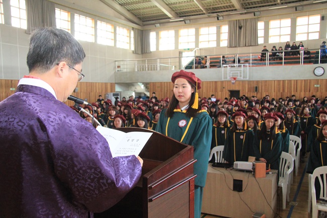  김윤기 교장이 졸업생 대표 성연주 학생에게 졸업장을 수여 하고 있다.